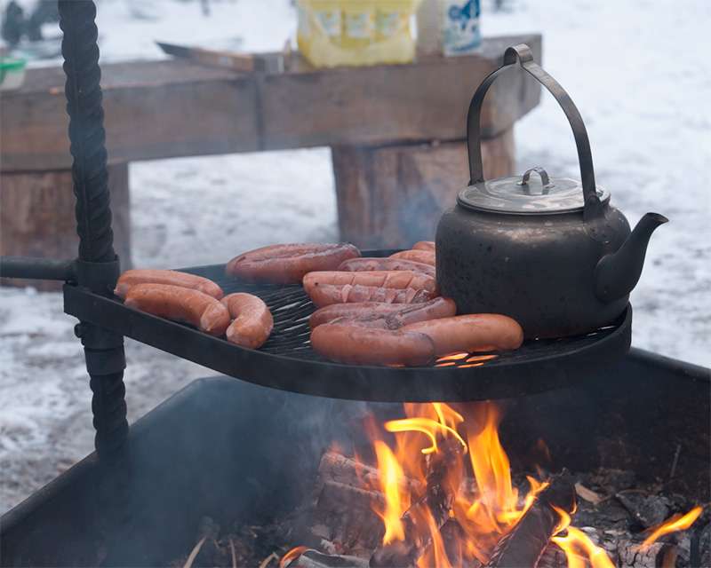 Sausages and a sooty kettle over an open fire at the Pilpasuo campfire site