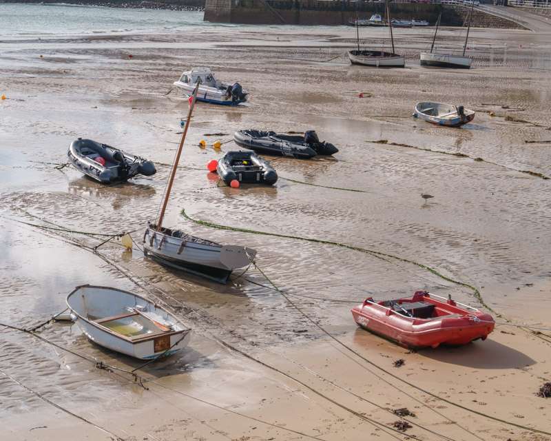 Boats sitting on the sand in the dried-out harbour of St Ives at low tide